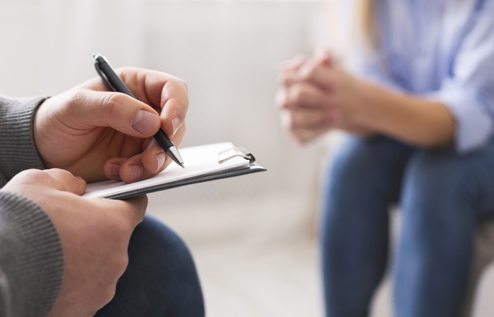 Cognitive Behavioural Therapy (CBT) in India. The picture shows a psychologist and a patient sitting. The psychologist make notes with a pen